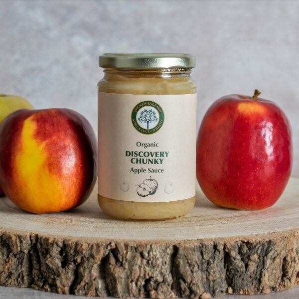 discovery chunky chilli apple sauce picture of jar on a rustic slab of wood with three red discovery apples