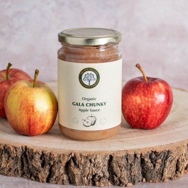 gala chunky applesauce on a rustic slab of wood with three gala apples