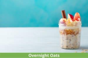 overnight oats jar with oatmeal appleslcies and cinnamon stick on white table with blue background