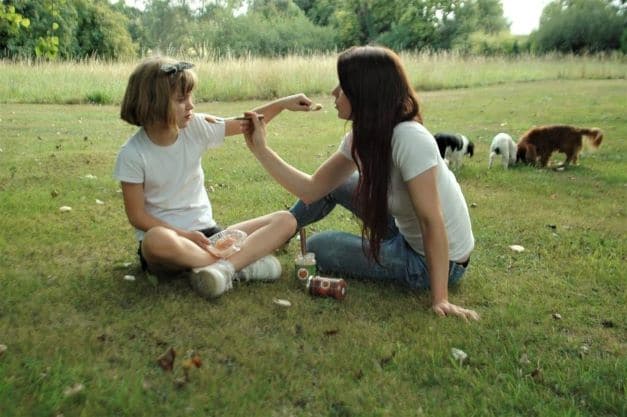 mother and daughter enjoying unsweetened apple sauce uk on the grass with dogs behind them. Thank you for your order
