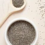 Picture of chia seeds in a bowl and on a wooden spoon. Lightly scattered on the table