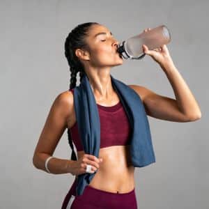 Woman athlete drinking from a reusable water bottle