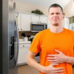 man with stomach trouble in the kitchen not having good gut health