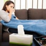 woman sitting on a couch with a blanket over her. showing signs of suffering from cold due to poor gut health.